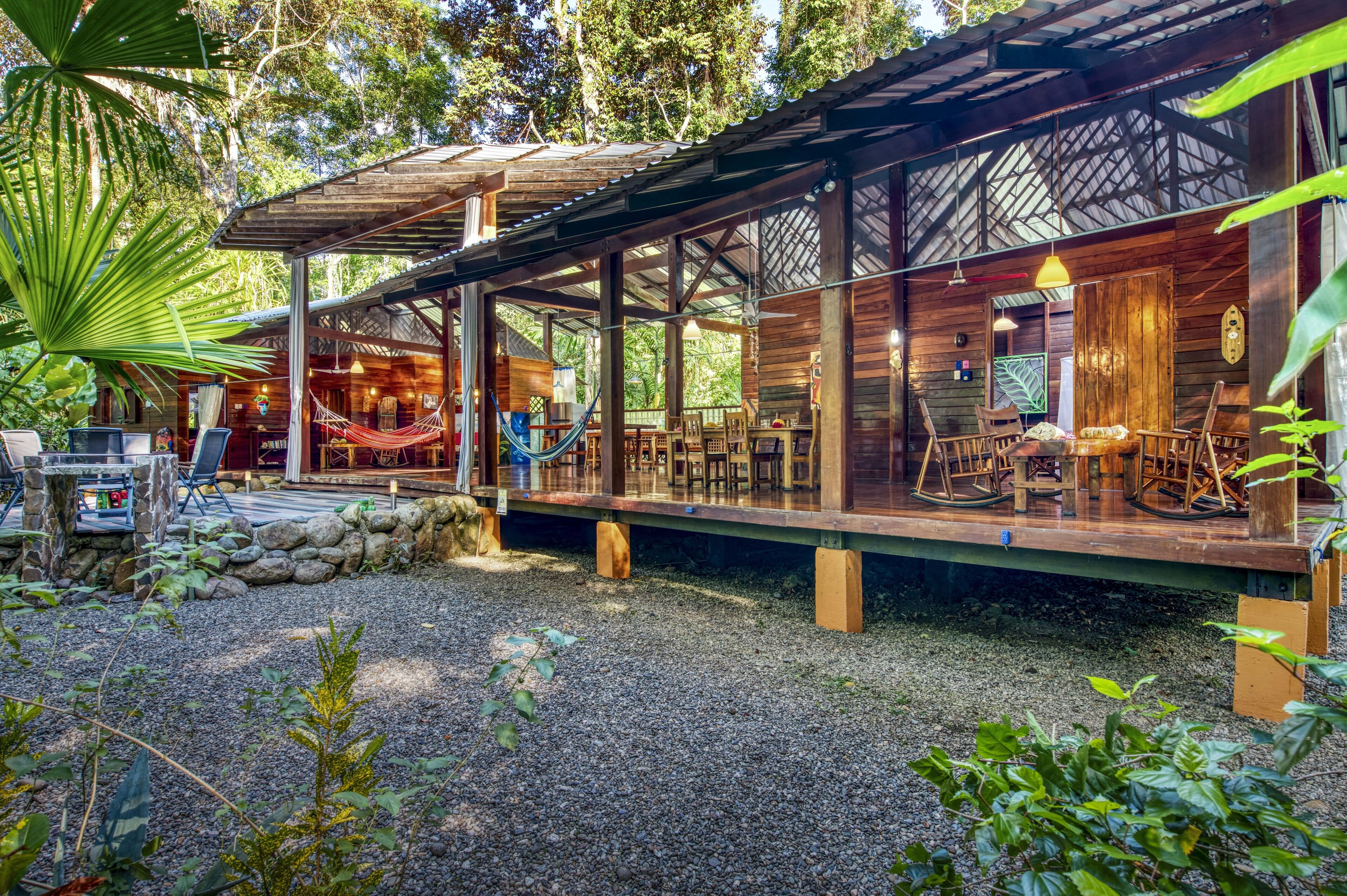 A wooden cabin with a covered patio, outdoor seating, and a hammock.