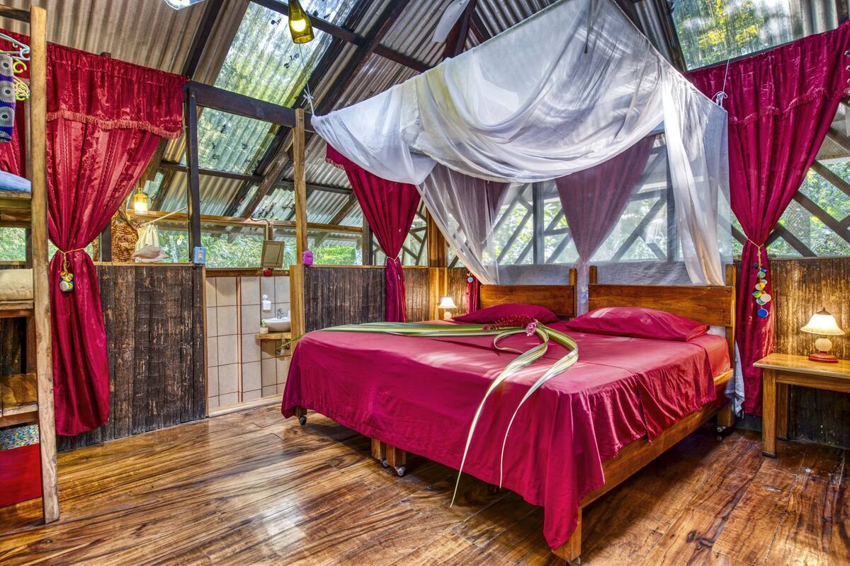A room with a wooden bed, red curtains, and a canopy.