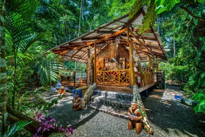 A rustic wooden structure surrounded by lush greenery, with a stone pathway leading to it. - Congo Bongo EcoVillage Costa Rica (Cahuita)
