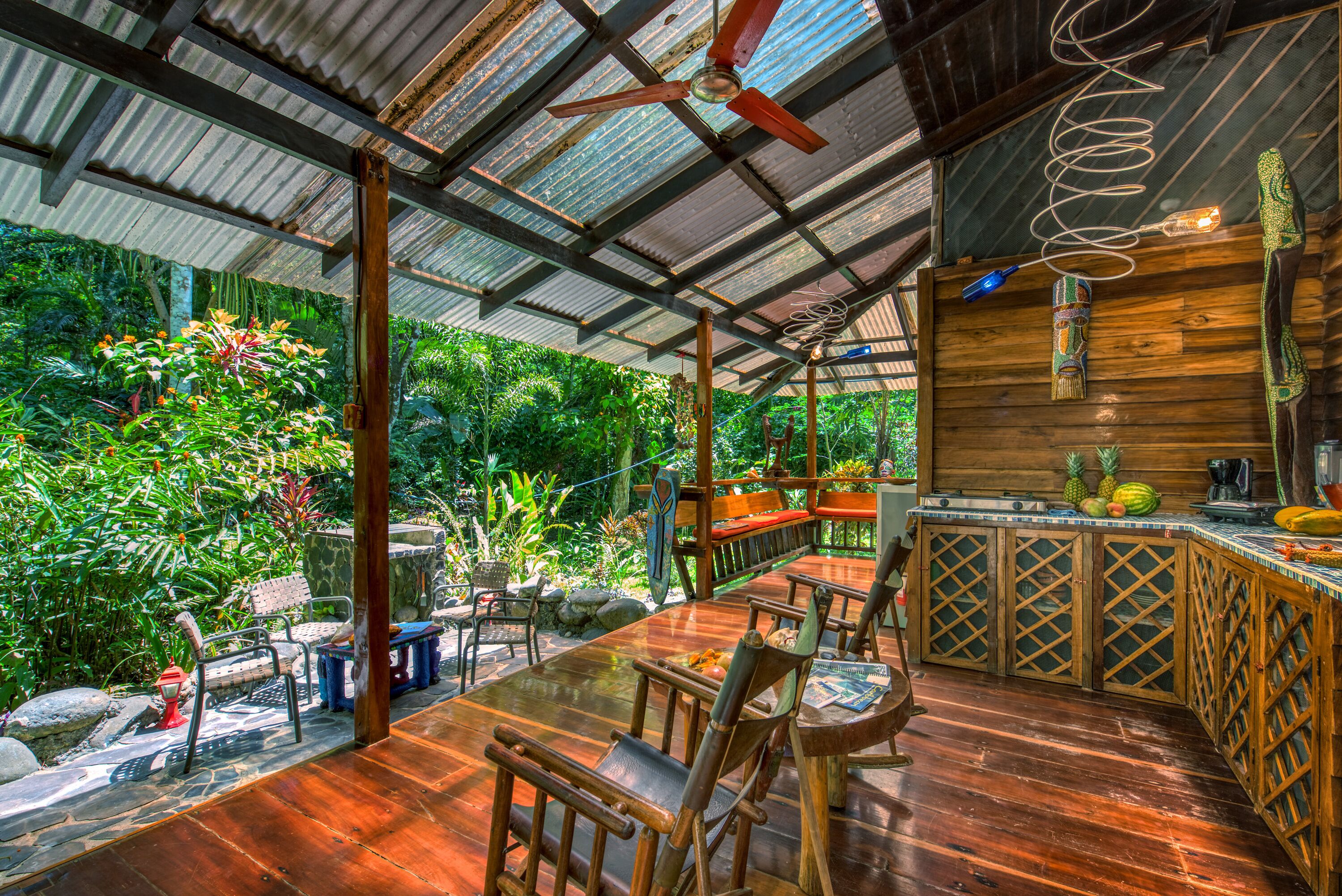 Una terraza de madera con comedor, barra y ventilador de techo.