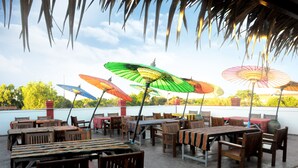An outdoor patio with wooden tables and chairs, surrounded by colorful umbrellas. - La Casa Di Bagan Nan Eain Thu (Nyaung-U)