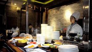 A buffet setup with various food items and stacked plates. - La Casa Di Bagan Nan Eain Thu (Nyaung-U)