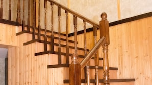 Una escalera de madera con barandilla y una puerta al final.