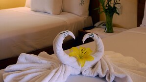 A hotel room with two beds, a vase with flowers, and a towel artfully arranged to resemble swans. - Hotel & Spa Villa Vergel (Ixtapan de la Sal)