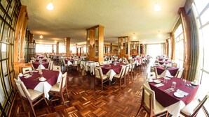 A dining area with multiple tables set for guests, wooden flooring, and large windows allowing natural light. - Hotel & Spa Villa Vergel (Ixtapan de la Sal)