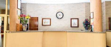 A reception area with a curved counter, framed pictures on the wall, and a clock.