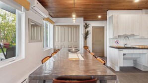 A modern kitchen with white cabinets, a wooden countertop, and a built-in sink. - Les Chalets Baie Cascouia (Larouche)