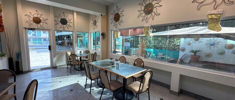 A restaurant interior with a long table, chairs, and decorative sun motifs on the walls.