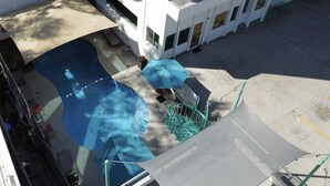 A modern building with a pool area, including a slide and a staircase leading to an upper level. - R INN de TJ (Tijuana)