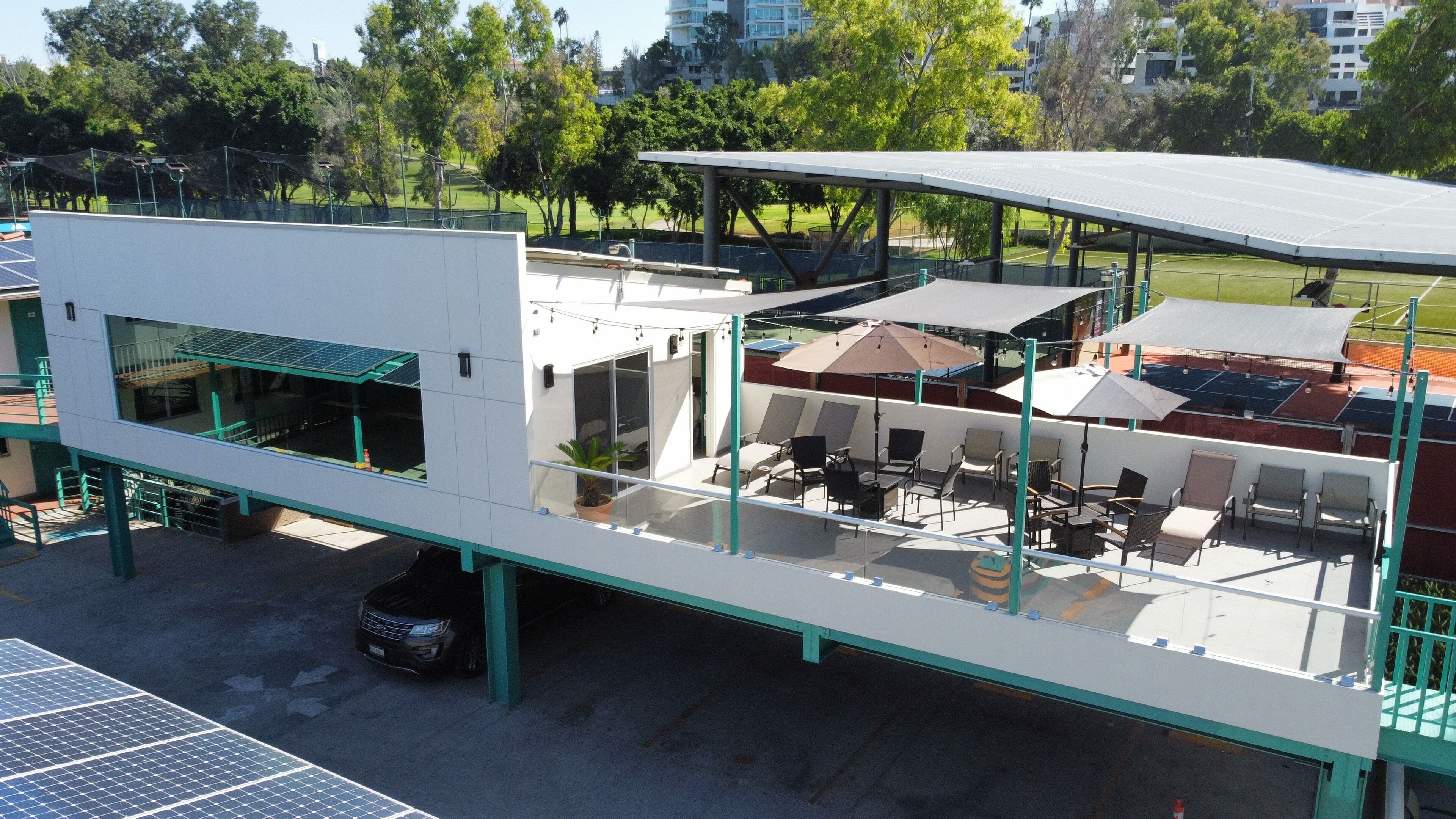 A modern building with a rooftop terrace featuring outdoor seating and solar panels.