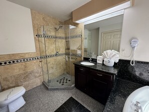 A bathroom with a glass-enclosed shower, a sink with a dark countertop, and a toilet.