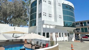 Un edificio moderno con zona de piscina, mobiliario exterior y cielo despejado.