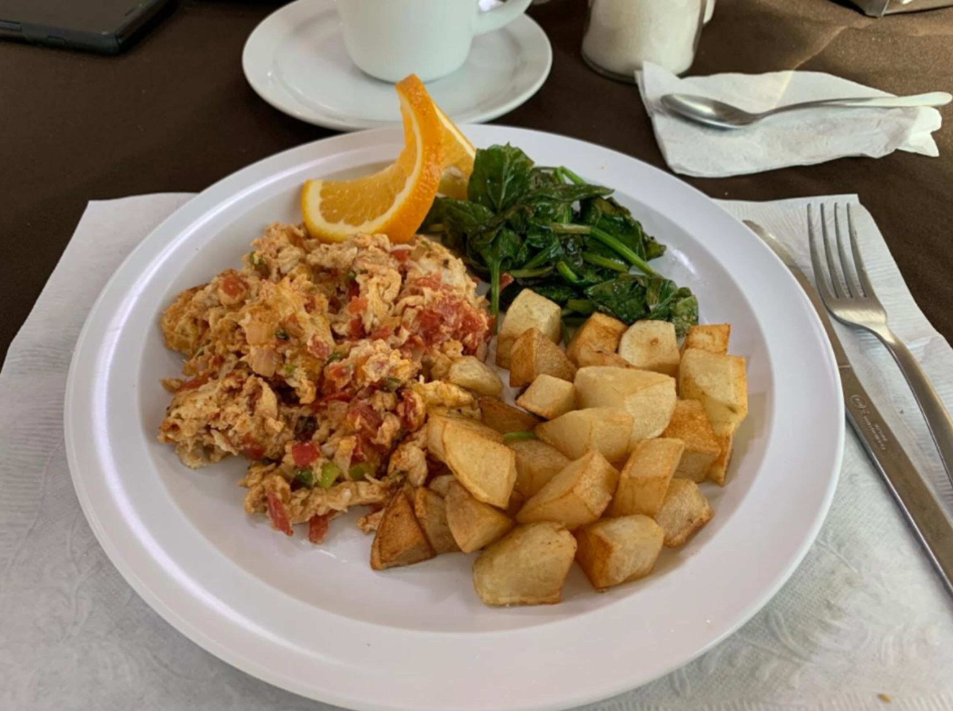 A plate with scrambled eggs, roasted potatoes, and sautéed greens.