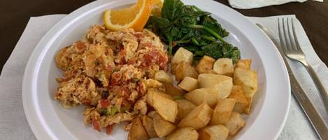 A plate with scrambled eggs, roasted potatoes, and sautéed greens.
