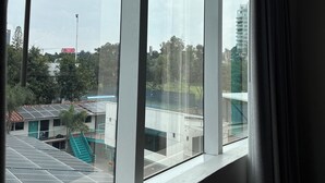 Una habitación con amplios ventanales que dan a unas instalaciones deportivas con paneles solares y un edificio con techo verde.