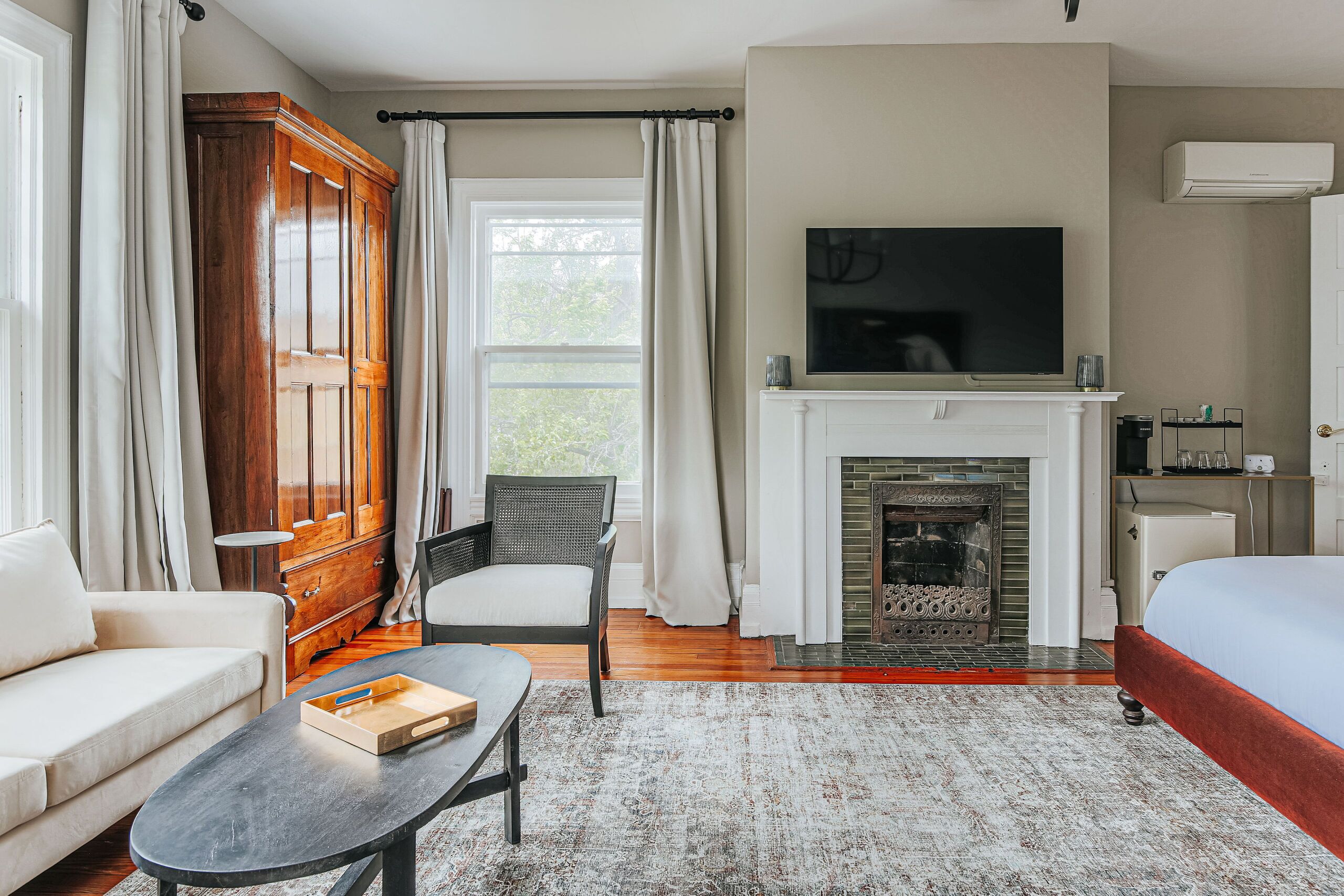 A hotel room with a sofa, a chair, a TV, a fireplace, and a bed.