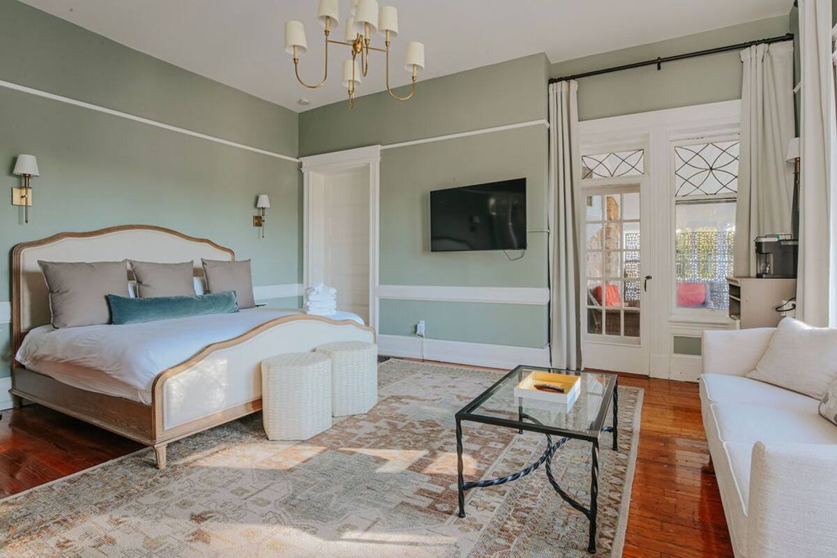 A bedroom with a bed, a TV, a sofa, and a coffee table.