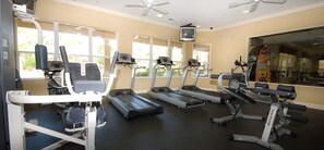 A fitness center with treadmills, weight machines, and a television.