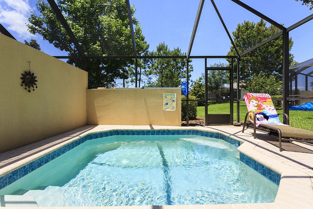 A swimming pool with a tiled edge, surrounded by a covered area with a metal frame.