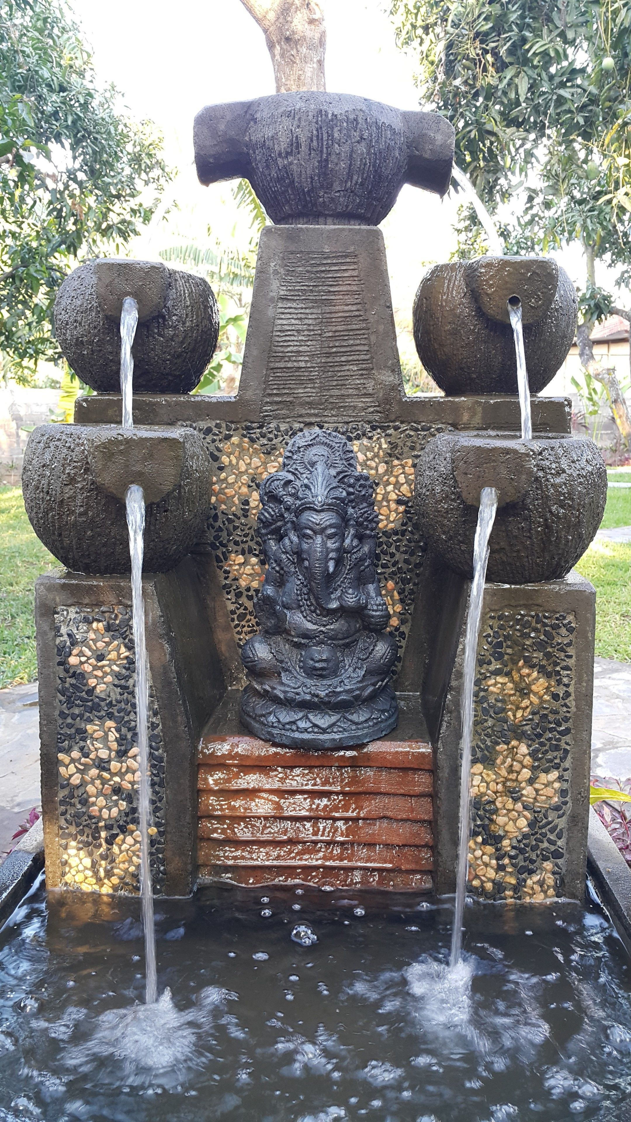 A stone water feature with a central sculpture and multiple water spouts.