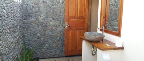 A bathroom with a stone wall, wooden door, and a stone sink.