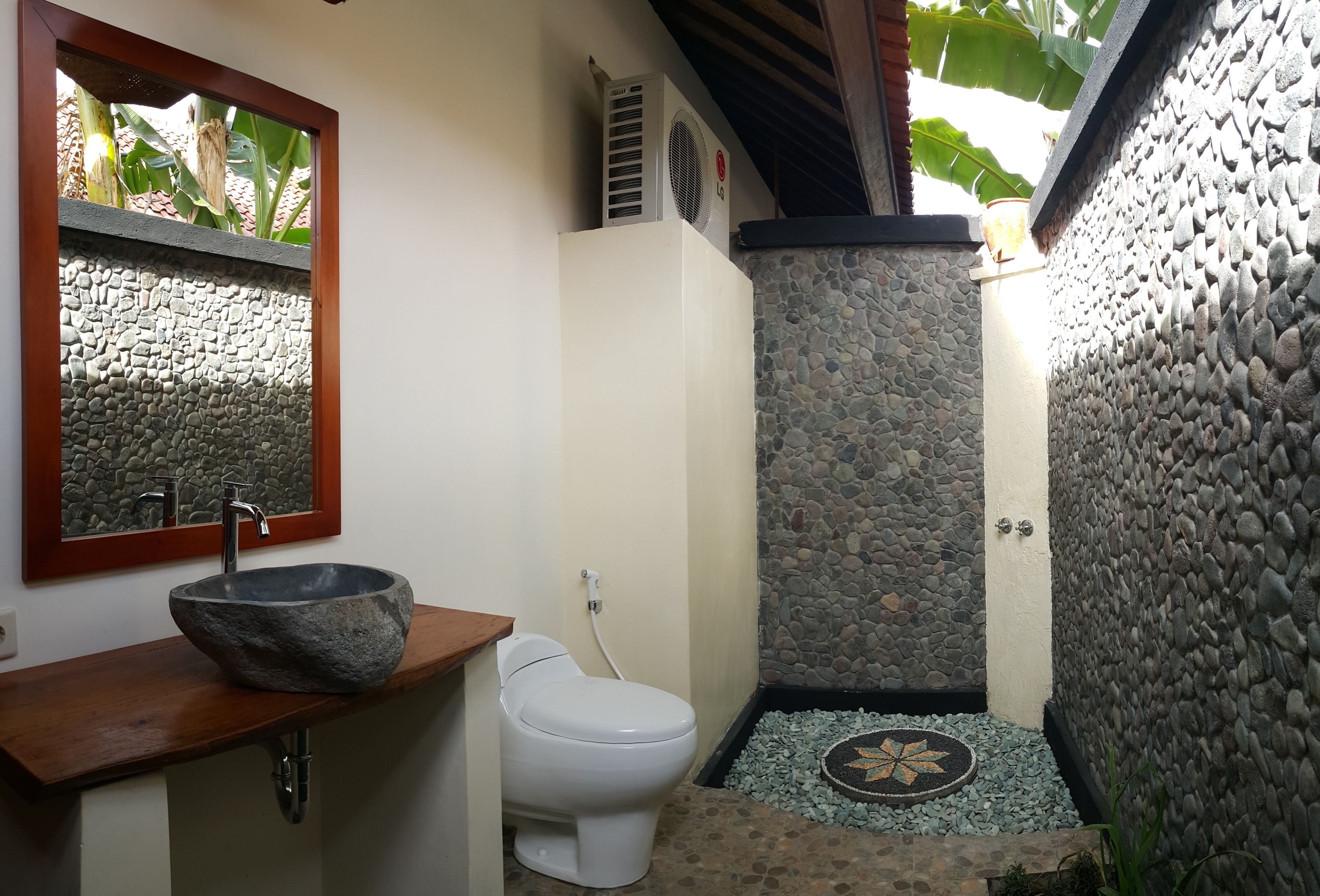 A bathroom with a stone sink, white toilet, and a stone wall.