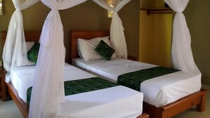 A room with two wooden beds, each with white bedding and green decorative pillows.
