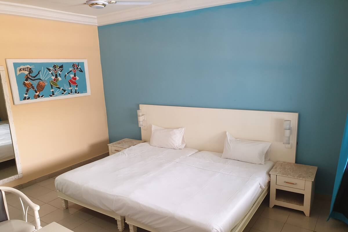A bedroom with a large bed, two bedside tables, a chair, and a painting on the wall.