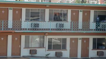 Un motel à deux étages, avec des portes numérotées, un balcon doté d’une rambarde en métal et des unités de climatisation.