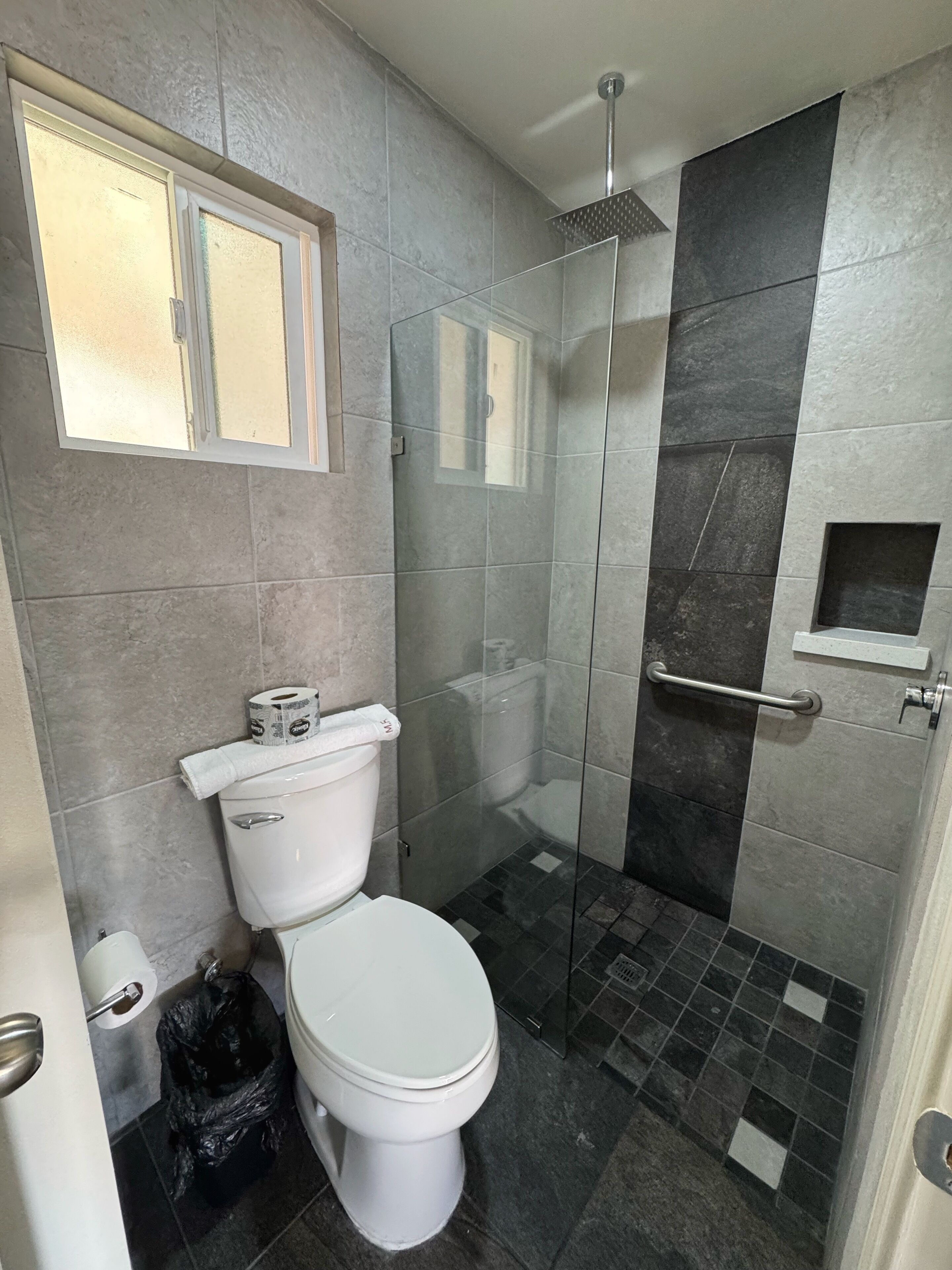 Un baño con inodoro, ducha y cabina de ducha con paredes de vidrio.