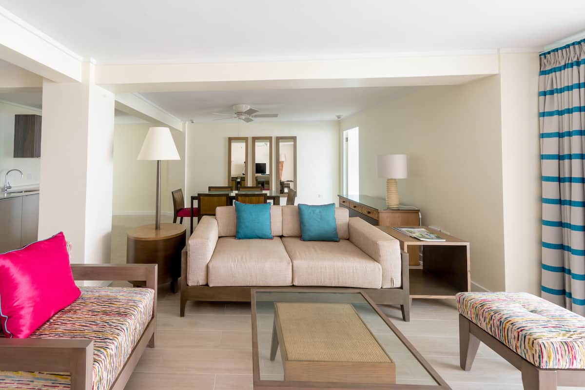 A modern living room with a sofa, two armchairs, a coffee table, and a dining area with a table and chairs.