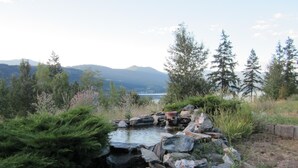 A natural landscape with a small waterfall, surrounded by rocks and vegetation, with mountains in the background. - Jade Mountain Motel (Chase)