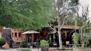An outdoor patio area with tables and chairs, a staircase, and a building with a red facade.