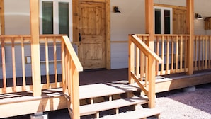 A wooden porch with a staircase leading to a door marked 106. - Halfway Hotel (Essex)