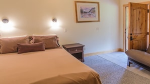 A bedroom with a bed, bedside tables, a chair, and a door. - Halfway Hotel (Essex)