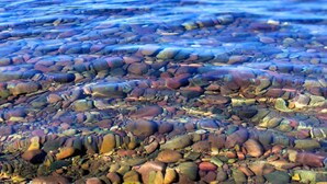 A clear lake with visible pebbles and mountains in the background. - Halfway Hotel (Essex)