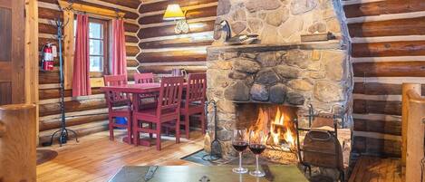 L’intérieur d’une cabane en rondins, avec une cheminée en pierre, des meubles en bois et un canapé en cuir.