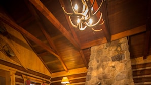 A log cabin interior with a stone fireplace, wooden furniture, and a cozy ambiance. - Storm Mountain Lodge Cabins & Dining (Castle Junction)