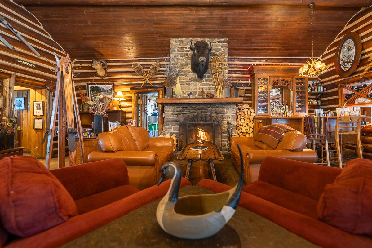 A cozy lounge area with leather sofas, a fireplace, and rustic decor including a buffalo head and antlers.
