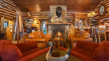 A cozy lounge area with leather sofas, a fireplace, and rustic decor including a buffalo head and antlers.