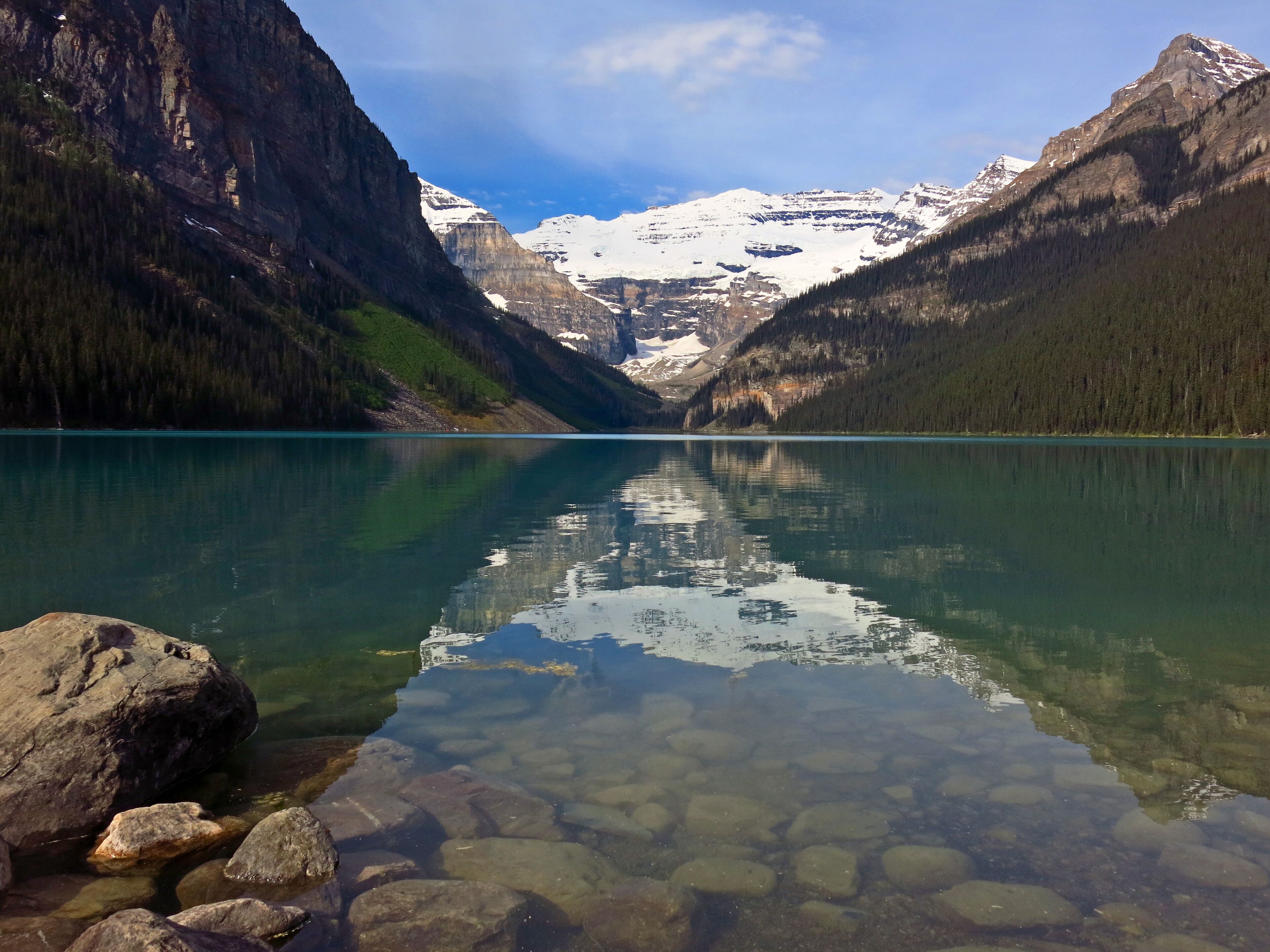 Un lago limpido con rive rocciose e montagne sullo sfondo.