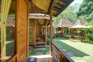 Een houten chalet met een veranda, een klein zitgedeelte en een tuin met een terras.
