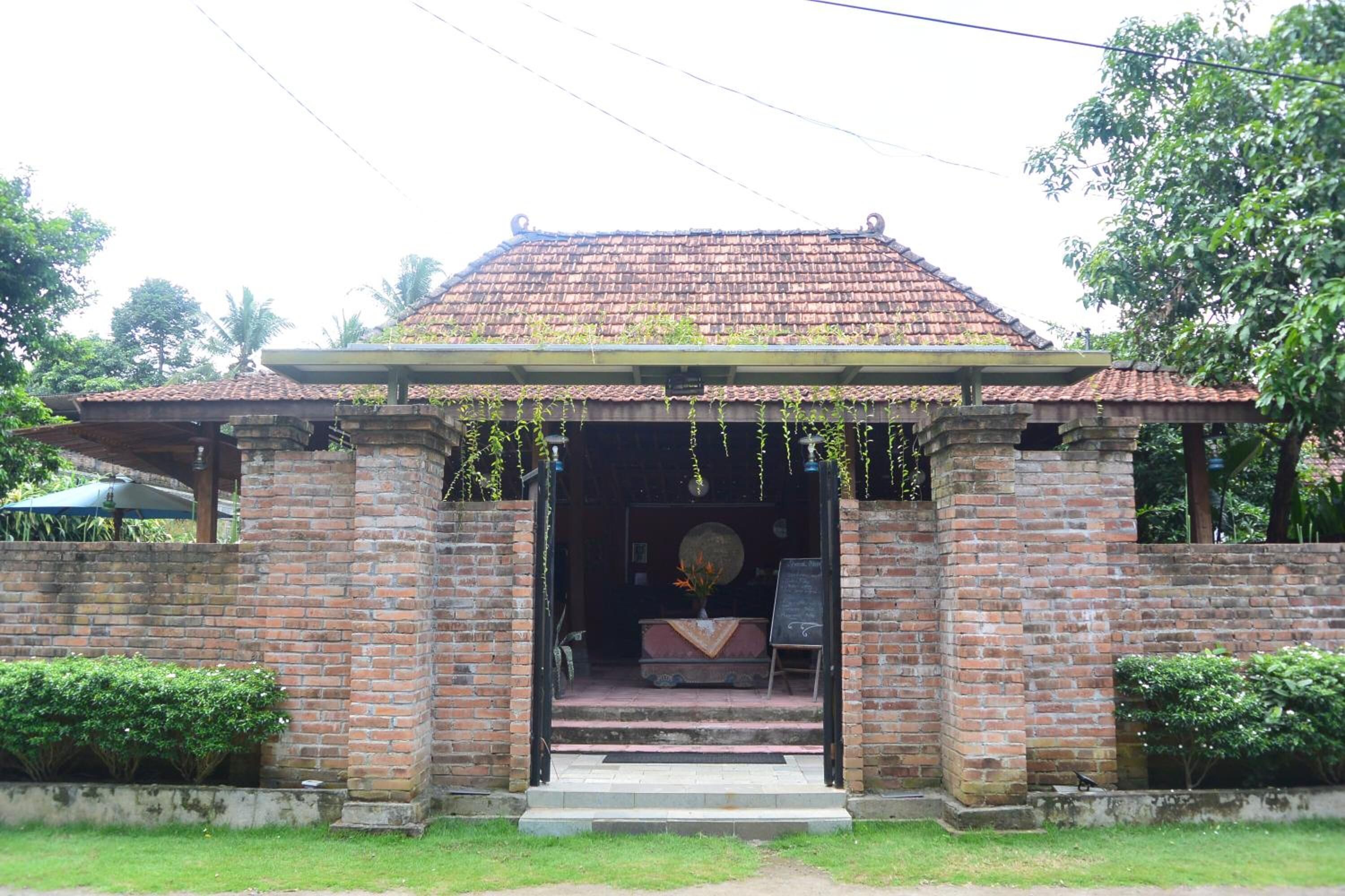 A brick building with a tiled roof, a small porch, and a signboard.