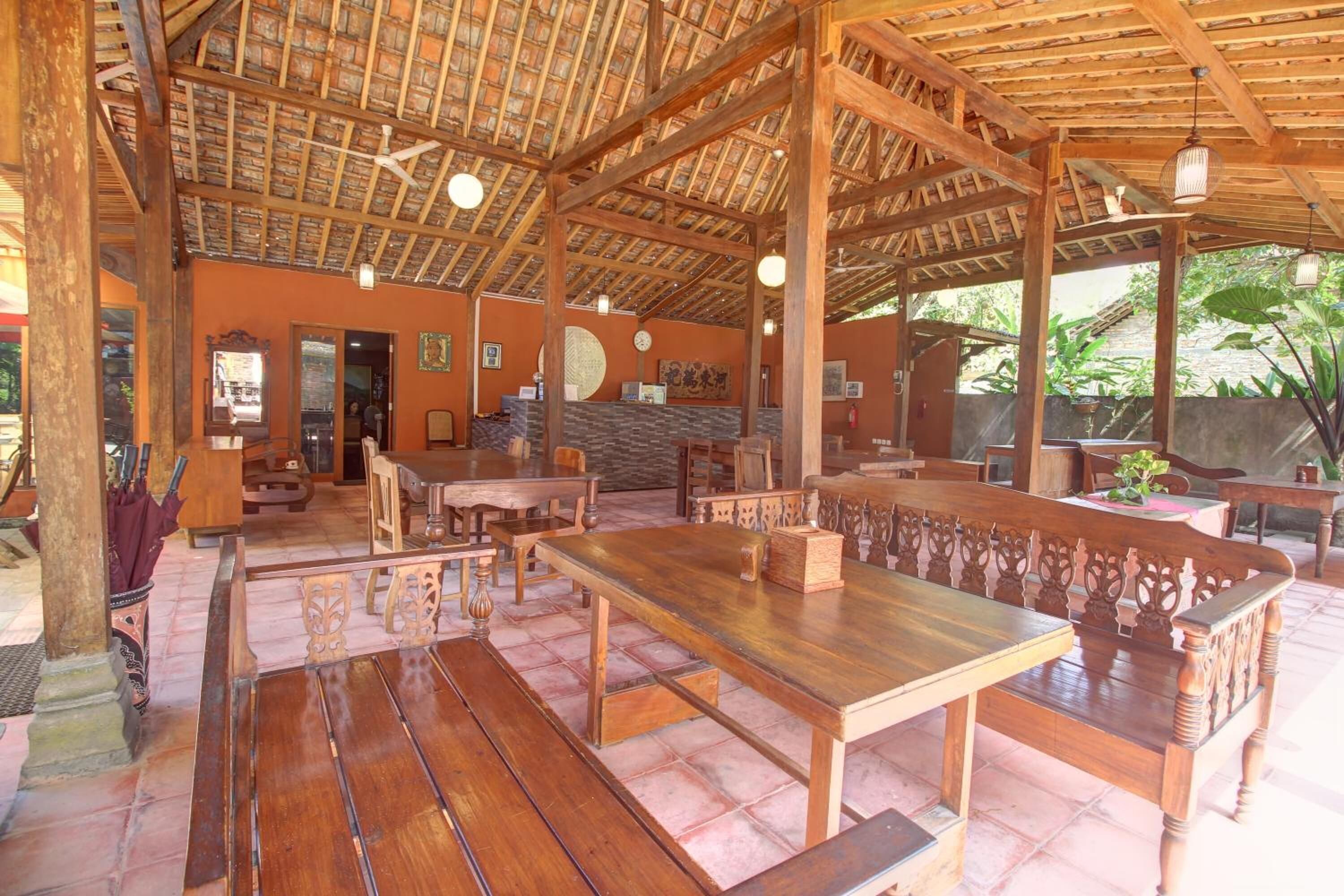 A spacious indoor area with wooden tables and benches, a high ceiling with a wooden framework, and a tiled floor.