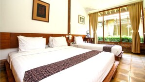 Ein Hotelzimmer mit zwei Betten, einem hölzernen Kopfteil, einem Telefon und einem Fenster mit Vorhängen.