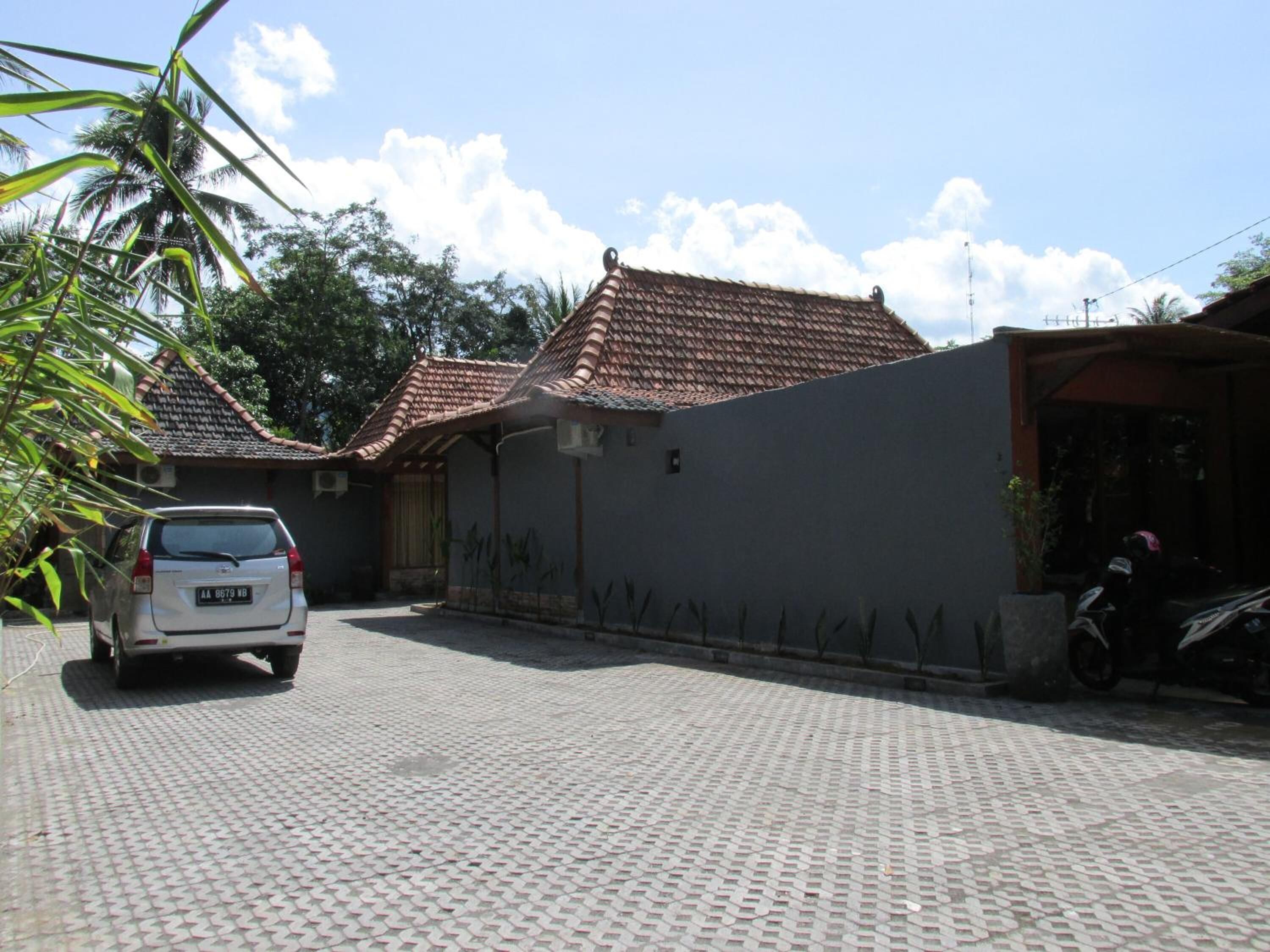 Un barrio residencial con entrada pavimentada, un coche estacionado y una motocicleta.