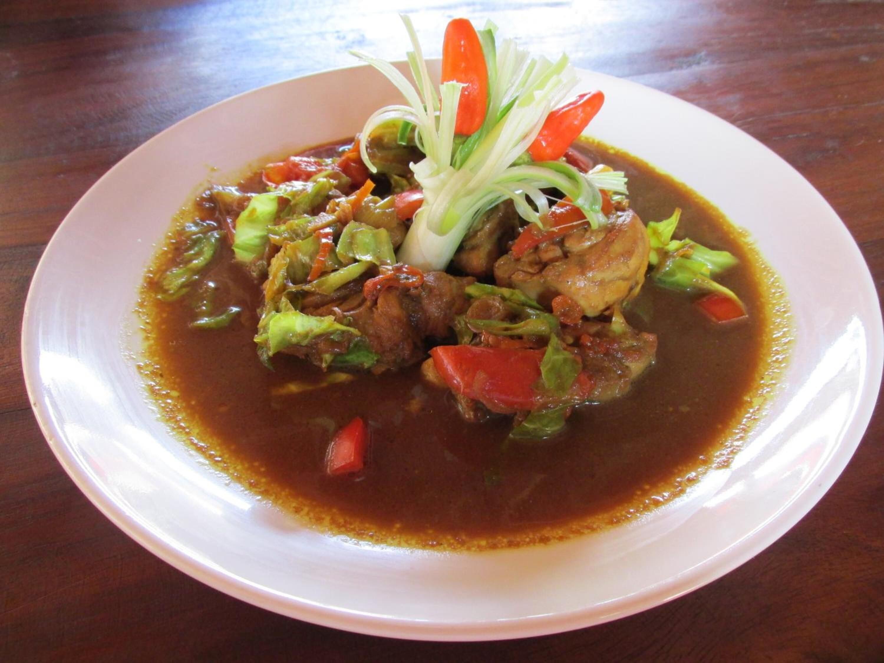 A plate of food with a clear broth and vegetables, served on a white plate.