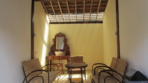 Ein Zimmer mit Holzboden, einem runden Tisch, zwei Stühlen, einem Spiegel und einem Mülleimer.