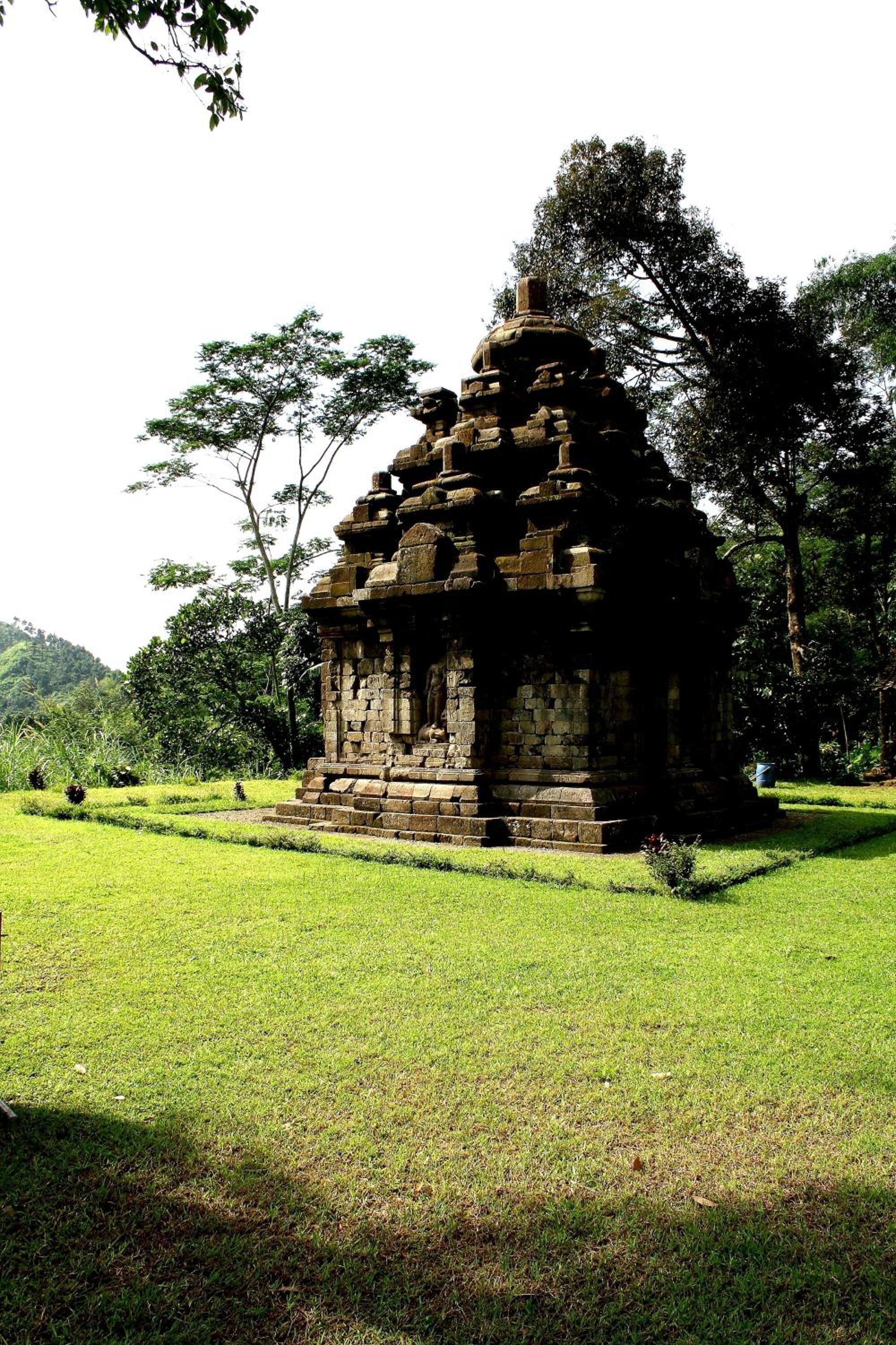 Un temple en pierre, entouré d’une pelouse bien entretenue, avec des arbres en arrière-plan.