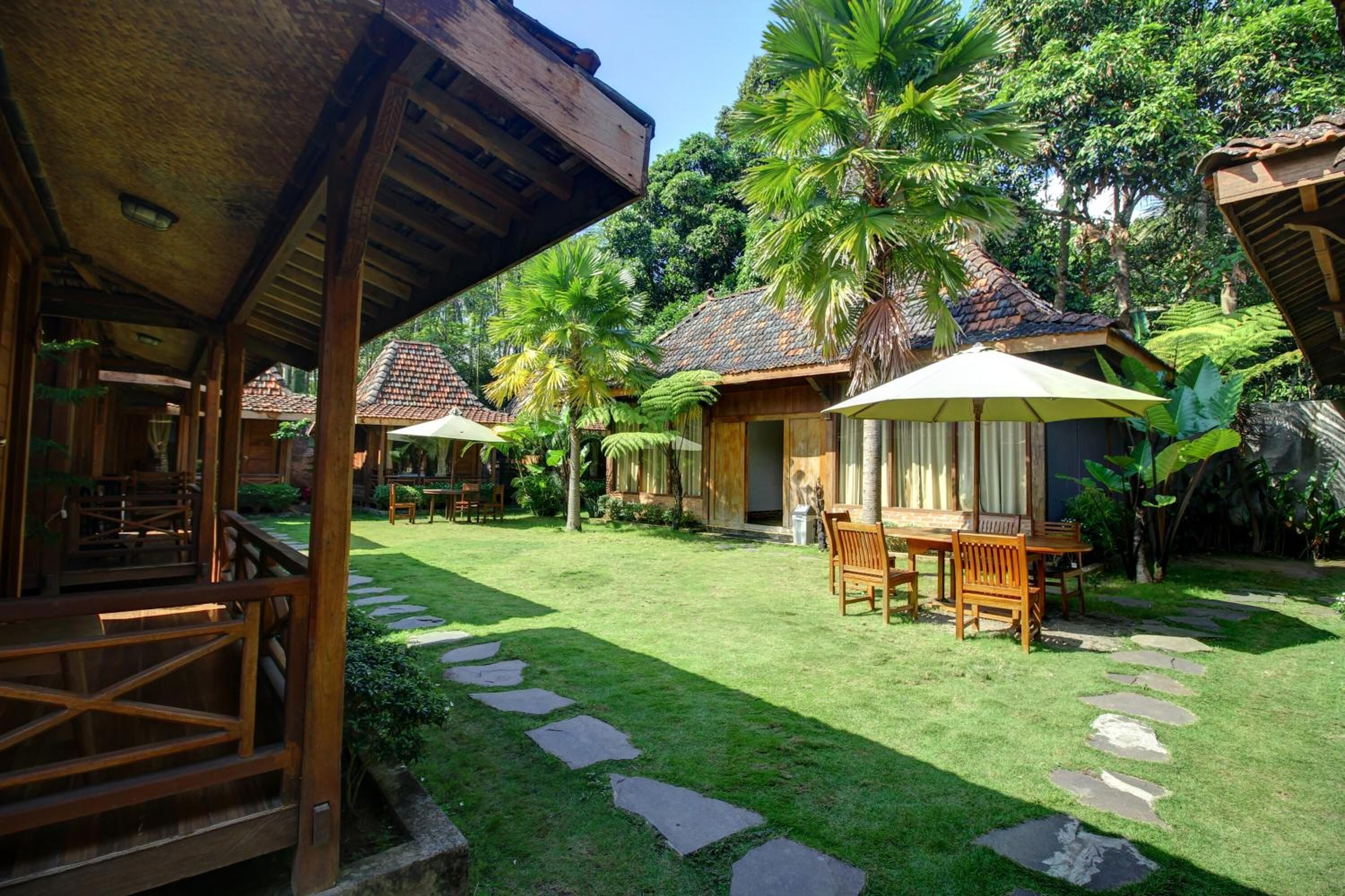 A wooden pavilion with a thatched roof, surrounded by a well-maintained lawn and stone pathways.